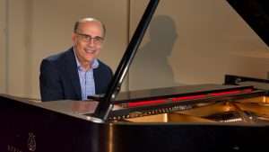 Master pianist Dr. Kevin Ayesh poses at a piano at Blue Ridge Community College in Flat Rock. (Photo by: Rich Keen.)